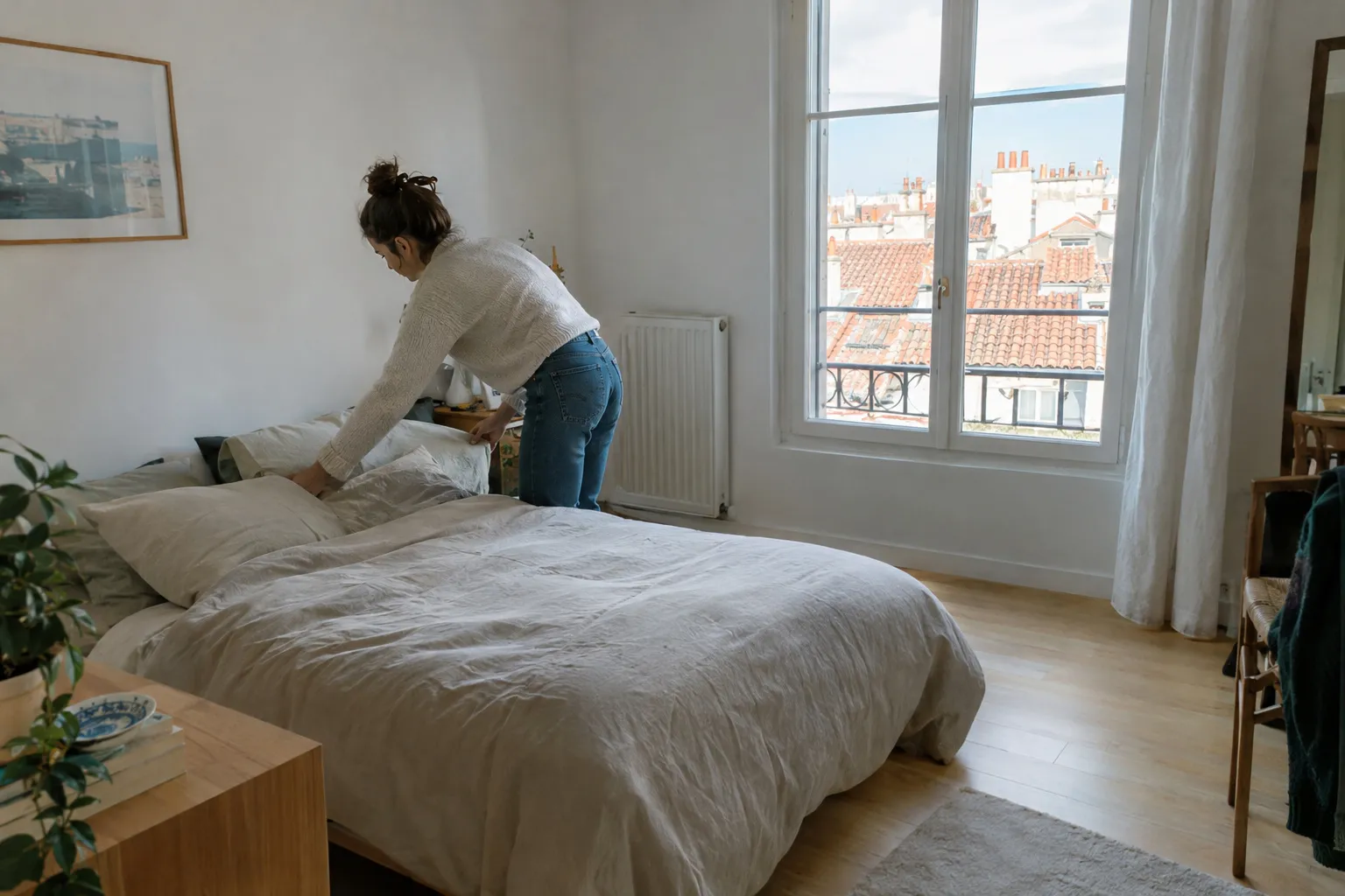 Chambre d’appartement rénovée avec parquet clair et vue sur les toits